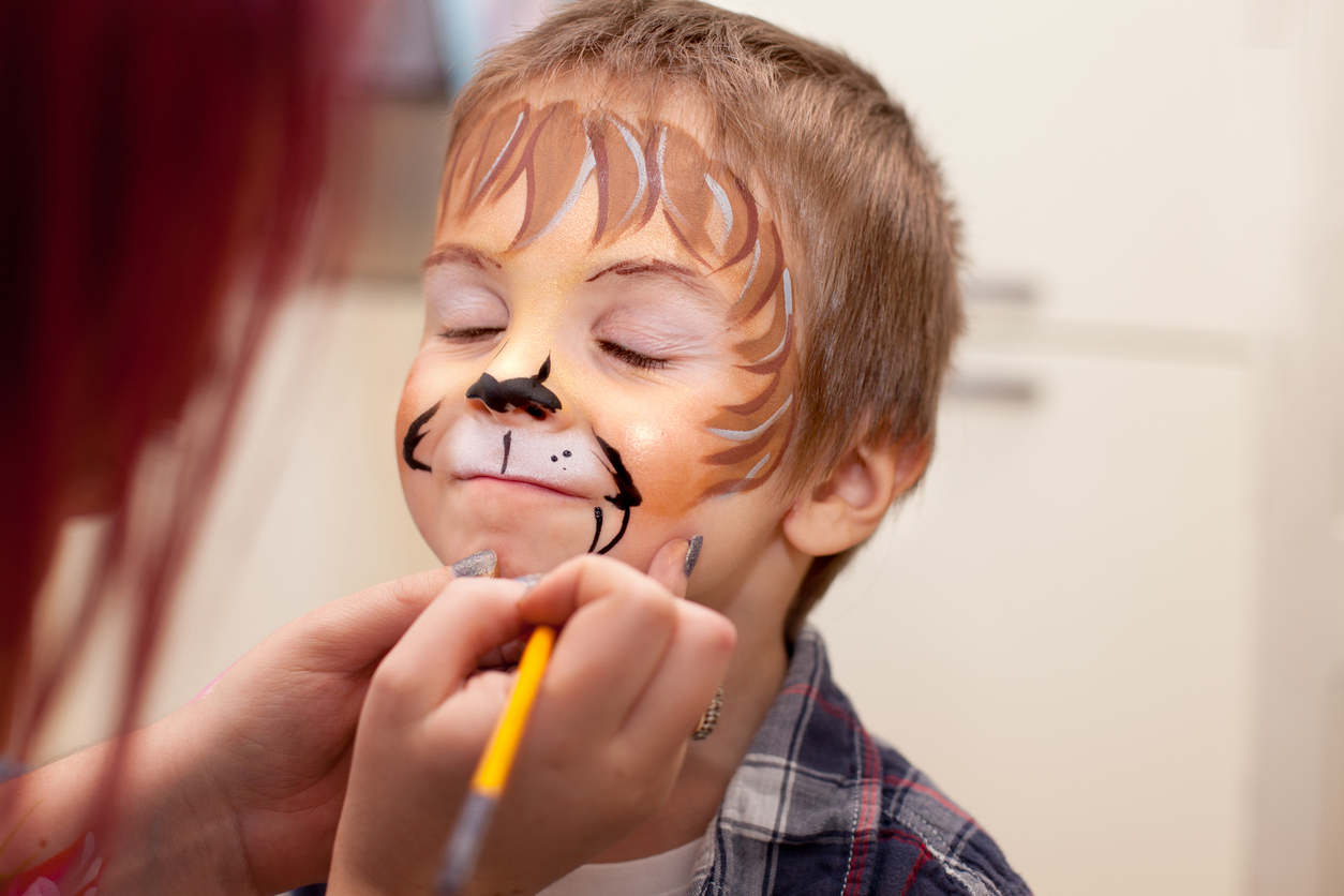 séance maquillage d'un enfant sur le thème des animaux. l'animatrice dessine un lion